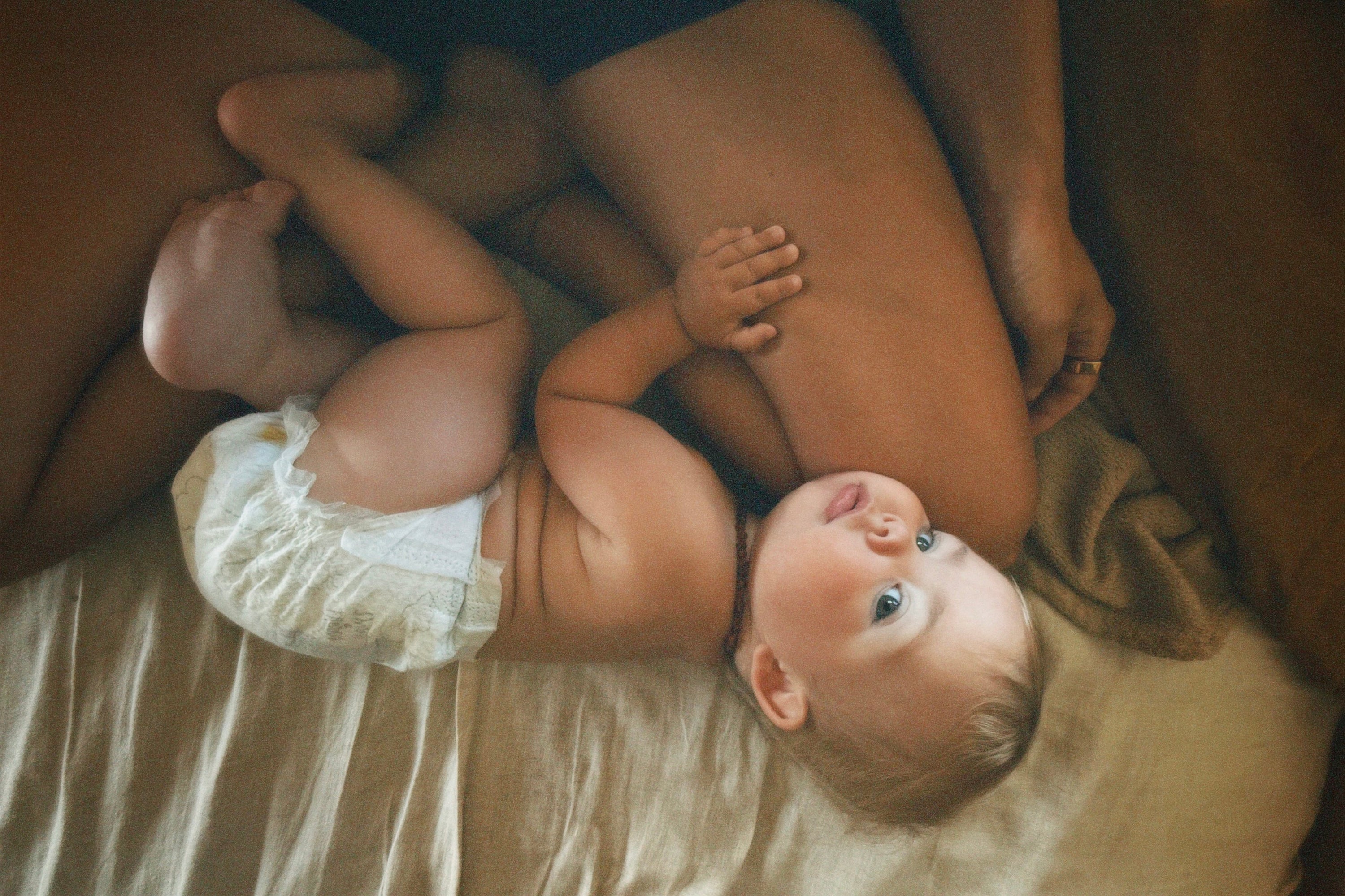 A small baby curled up between mothers legs.